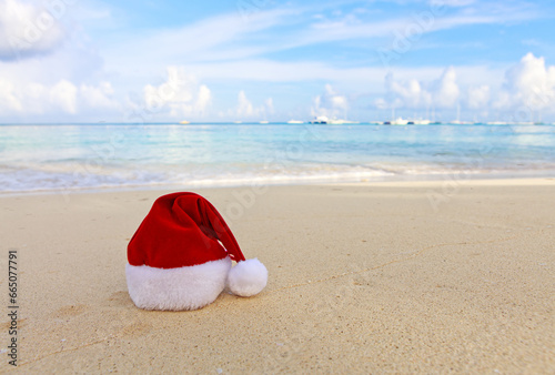 Merry Christmas background with red hat on the white Caribbean sand.
