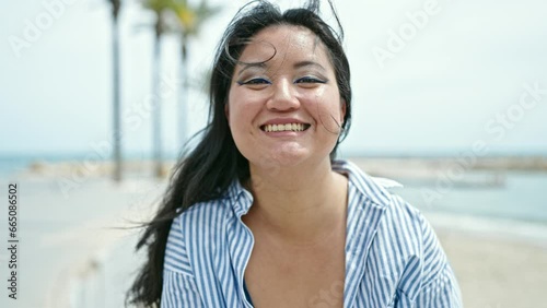 Young chinese woman tourist blowing kiss smiling at seaside photo