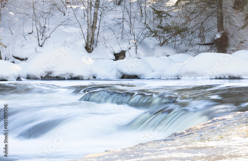 Rapids flowing in frozen river during hike © Riley
