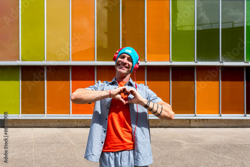 Man making heart gesture with hands near colorful building photo