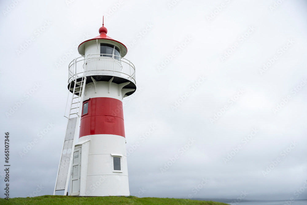 Lighthouse on grassy coast against ocean Lighthouse on grassy coast against ocean