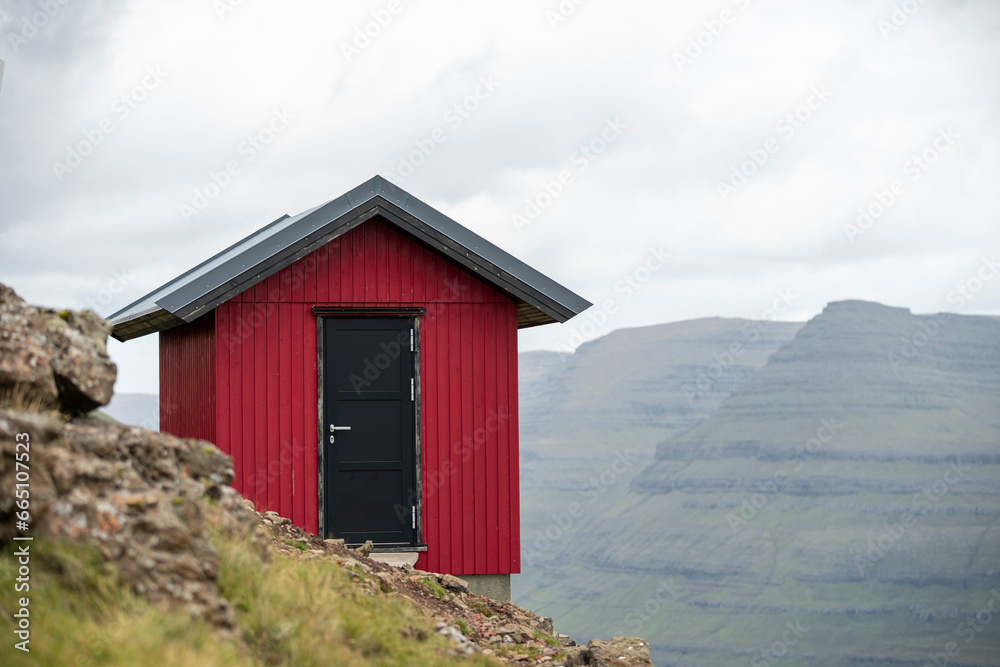 Red house on hill in mountainous valley Red house on hill in mountainous valley