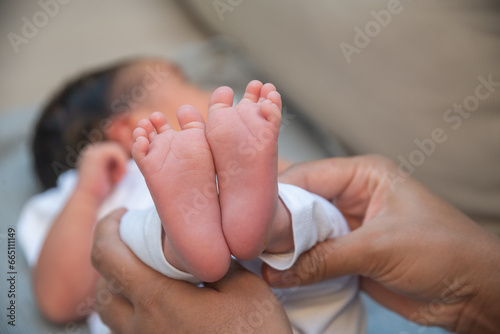 Crop faceless mother touching feet of cute infant photo