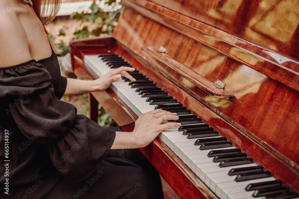 Fototapeta premium The girl plays the vintage piano at a concert.