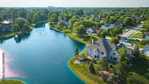 Large rich houses next to manmade pond with water fountain aerial