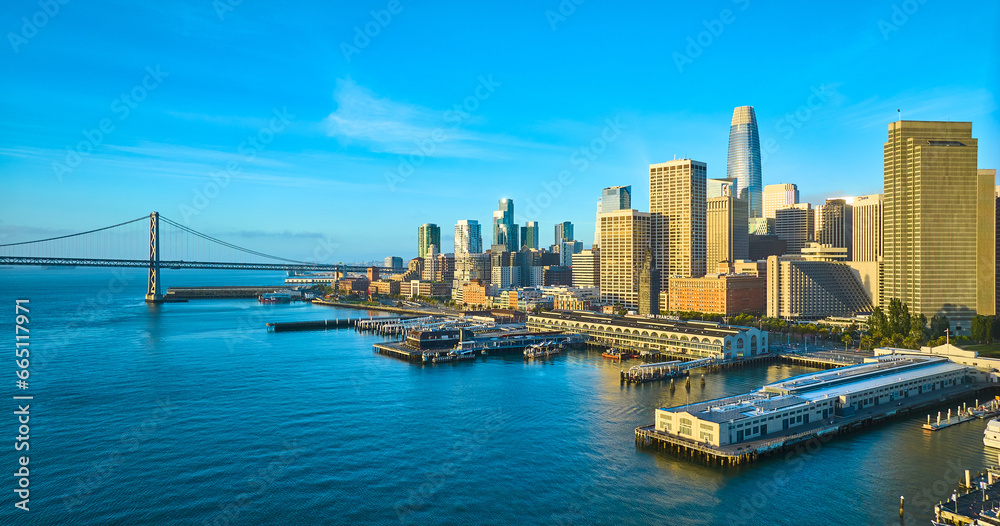 Wide aerial of San Francisco harbor with Oakland Bay Bridge leading to skyscrapers near sunrise Wide aerial of San Francisco harbor with Oakland Bay Bridge leading to skyscrapers near sunrise