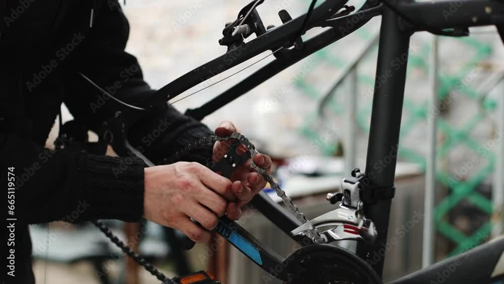 A young man disconnects a chain on a bicycle. A young man disconnects a chain on a bicycle.