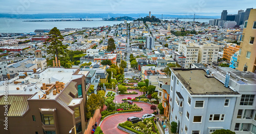Aerial winding Lombard Street with cars going downhill with distant Coit Tower