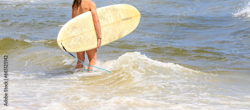 Surfer staniding on the waters edge ready to go into the ocean to surf