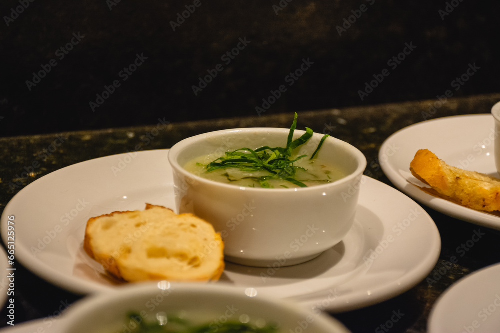 Delicious Portuguese green soup in a white mug, white plate with toast Delicious Portuguese green soup in a white mug, white plate with toast