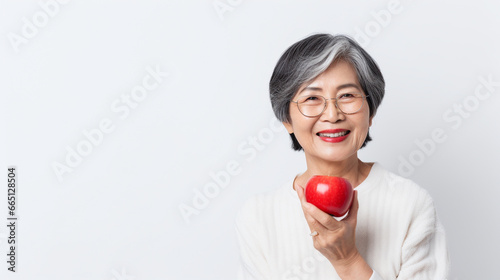 Asian old woman holding a red apple on a white background