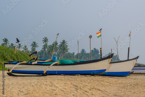 old fishing boats in the sand on the ocean in India on blue sky background photo