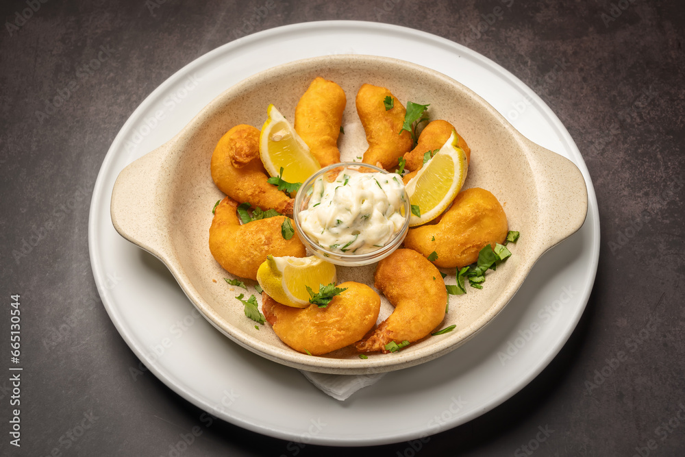 Deep fried scallops with French fries, lemon tartar sauce and herbs in a vintage plate.