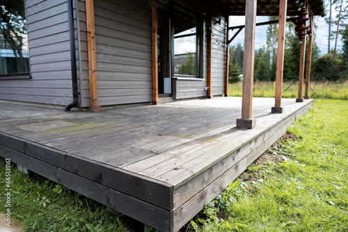 Old weathered wooden deck and new facade of a modern house