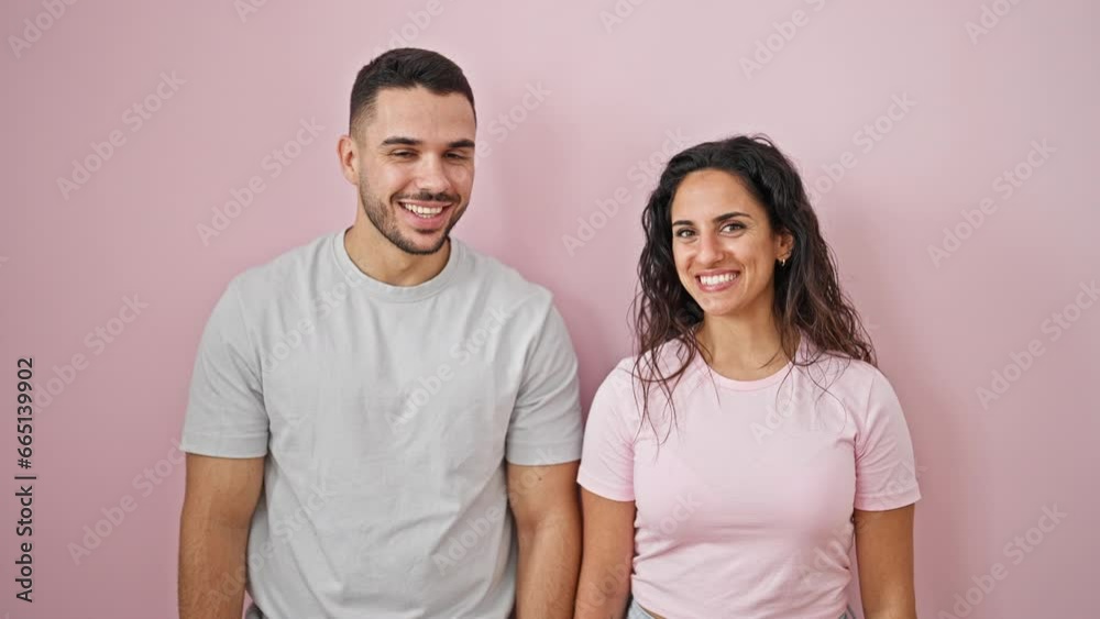 Man and woman couple standing together with surprise expression over isolated pink background Man and woman couple standing together with surprise expression over isolated pink background