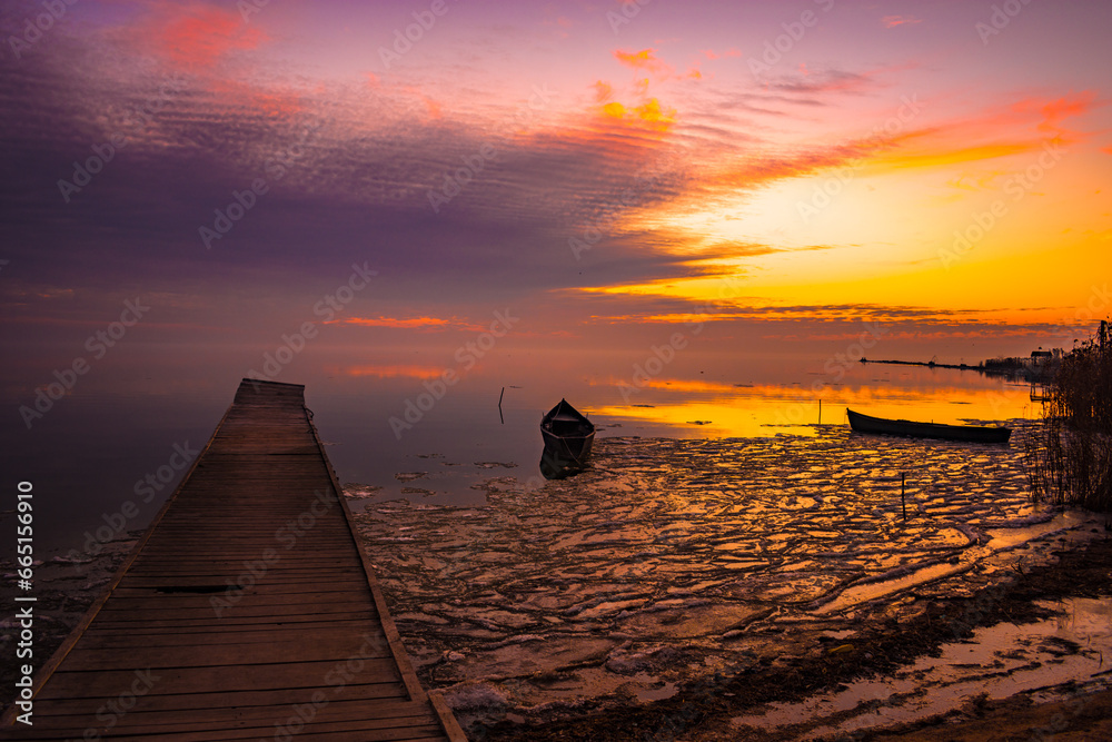 frozen boat in winter on the lake at sunrise