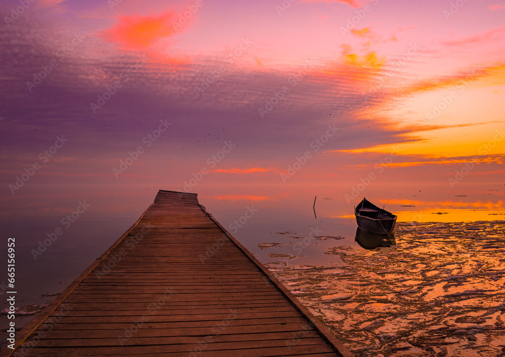 frozen boat in winter on the lake at sunrise