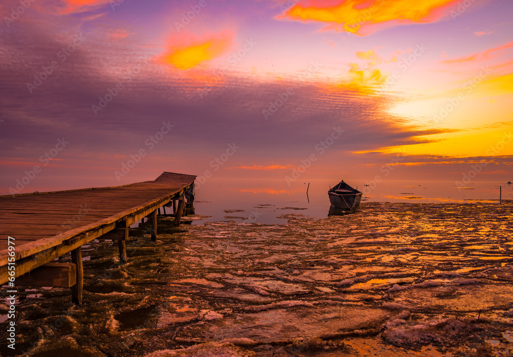 frozen boat in winter on the lake at sunrise