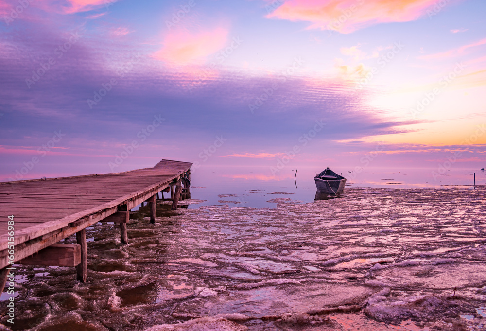 frozen boat in winter on the lake at sunrise