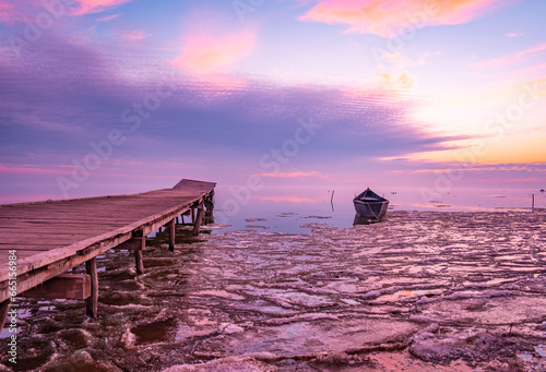 frozen boat in winter on the lake at sunrise