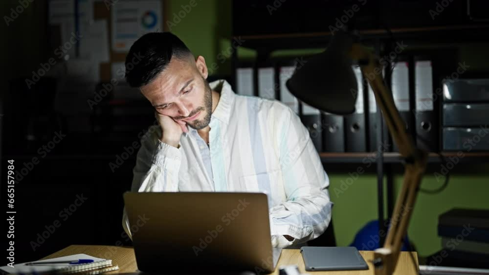 Young hispanic man business man tired looking watch leaning on table to sleep at the office Young hispanic man business man tired looking watch leaning on table to sleep at the office