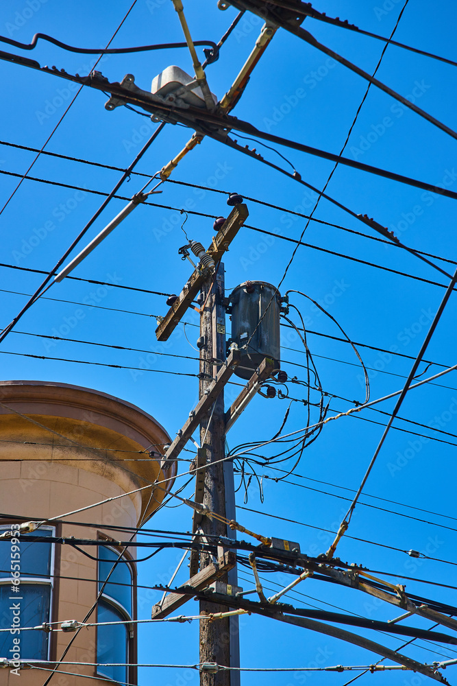 Telephone pole with clear blue sky behind it and mess of crisscrossing wires for electric city bus Telephone pole with clear blue sky behind it and mess of crisscrossing wires for electric city bus