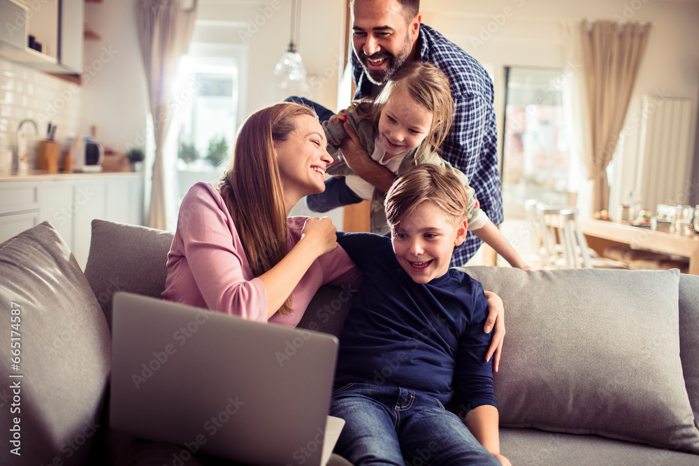 Happy young family spending time together with a laptop in the living room Happy young family spending time together with a laptop in the living room