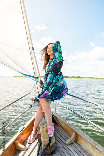 Beautiful young brunette girl in a dress on a yacht goes on a summer trip