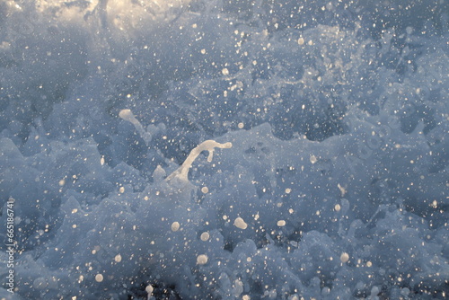 Close up of sea waves at sunset with orange light reflecting from the water