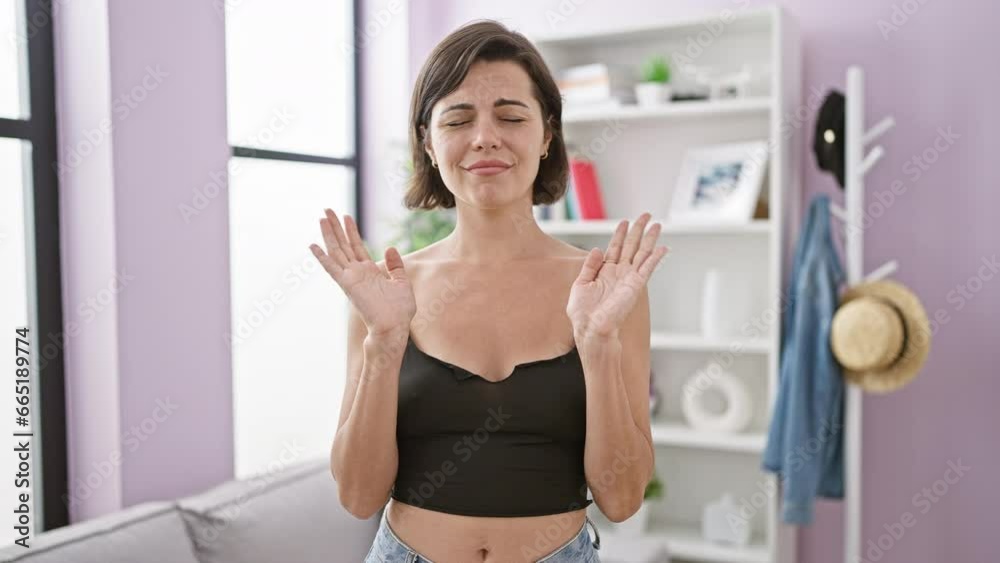 Stunning young hispanic woman adamantly displays stop gesture with arms at home, expressing refusal in her beautifully furnished living room. Stunning young hispanic woman adamantly displays stop gesture with arms at home, expressing refusal in her beautifully furnished living room.