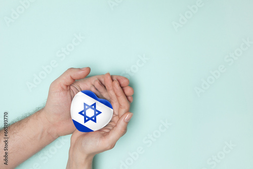 Heart with print of Israel flag in female and male hands. Flat lay.