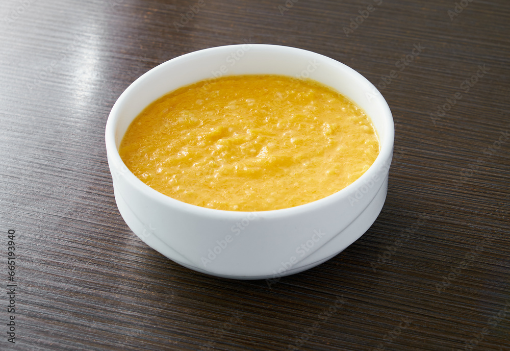 A bowl of pumpkin porridge on a textured dark brown table - an appetizing blend of Thanksgiving and healthy dining, embodying the essence of nourishing traditions.