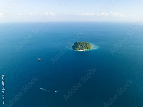 An idyllic, tropical island, surrounded by coral reef, is found in the Dampier Strait of Raja Ampat. This area is known as the heart of the Coral Triangle due to its incredible marine biodiversity. photo