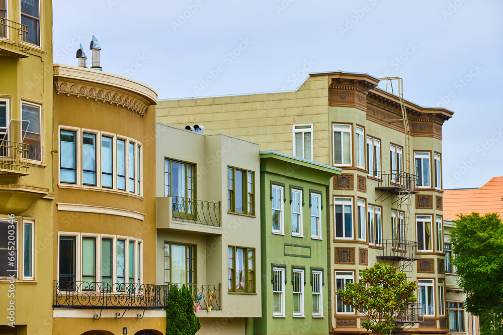 Fototapeta premium Row of houses and apartment buildings side by side with fire escape ladders on end and bay windows