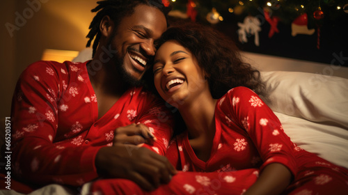 Happy african american couple lying in bed in christmas pajamas.