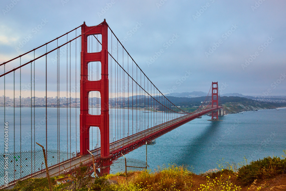 Naklejka premium Cloudy and hazy sunset from Golden Gate Bridge overlook with view of bridge and bay