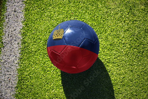 football ball with the flag of liechtenstein on the green field near the white line