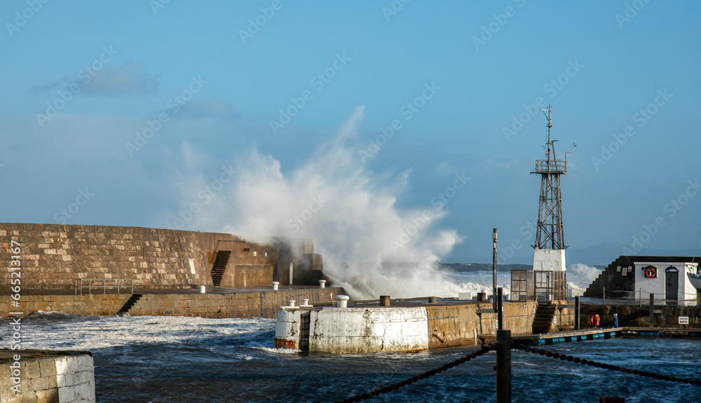 Storm Babet hitting a harbour wall with big waves over the wall in Scotland 