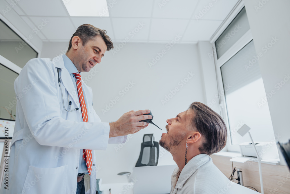 Obraz premium Doctor using video laryngoscope checking young patients throat.