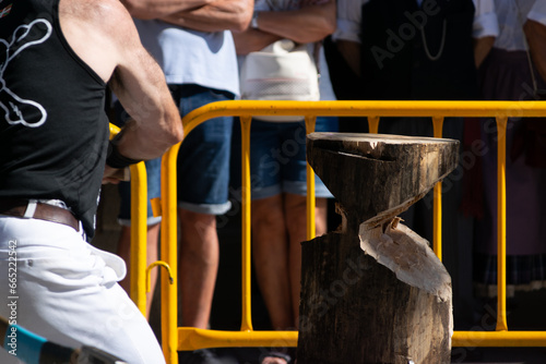 image of a fibered person cutting a log with an axe by hand during a competition exhibition in the Basque country photo