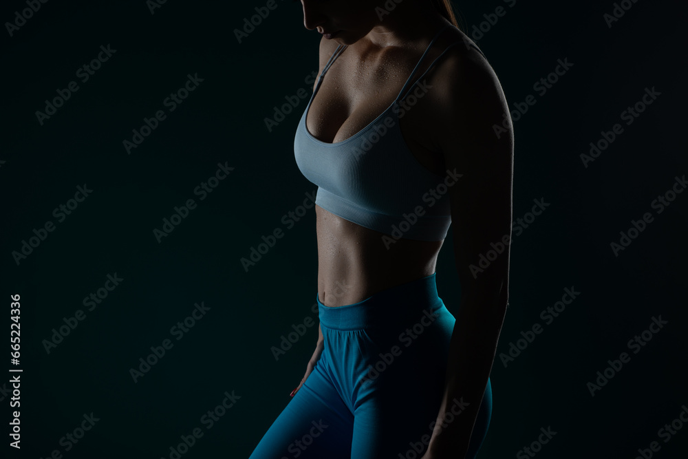 Naklejka premium A confident female fitness instructor does body exercises and stretches in a studio, inspiring motivation and progress.