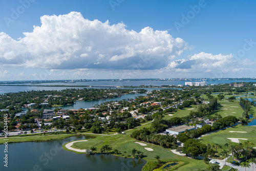 Aerial shot of a gorgeous summer landscape at Miami Beach Golf Club with lush green grass and trees, blue ocean water, homes and hotels in the skyline in Miami Beach Florida USA © Marcus Jones
