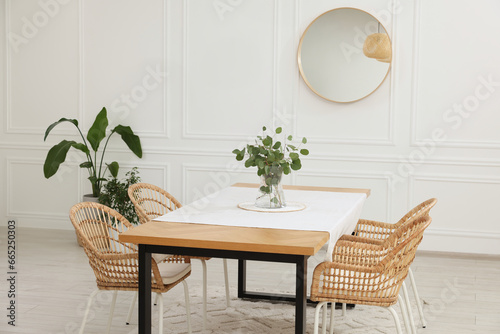 Stylish dining room with cozy furniture, mirror and plants