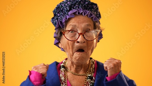Closeup portrait of toothless elderly senior old woman with wrinkled skin having great happy success winner wearing US flag jacket isolated on yellow background. People emotions concept.