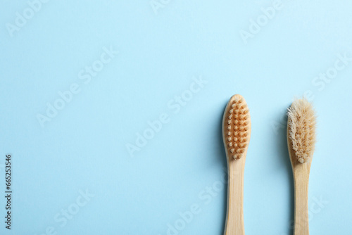 Two bamboo toothbrushes on light blue background  flat lay. Space for text