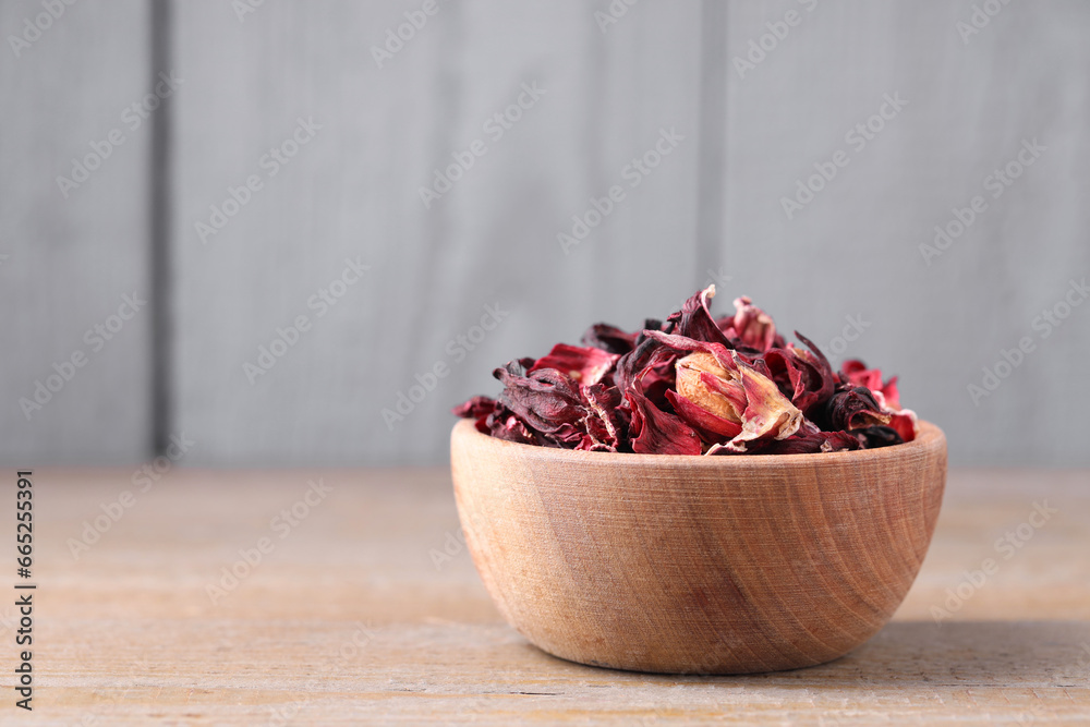 Dry hibiscus tea in bowl on wooden table, space for text Dry hibiscus tea in bowl on wooden table, space for text