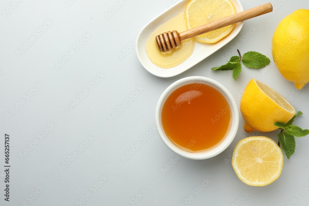 Sweet honey and fresh lemons on white table, flat lay. Space for text Sweet honey and fresh lemons on white table, flat lay. Space for text