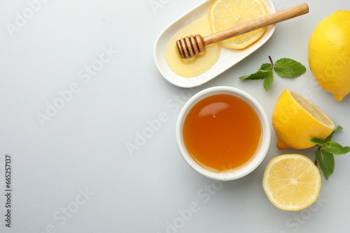 Sweet honey and fresh lemons on white table  flat lay. Space for text