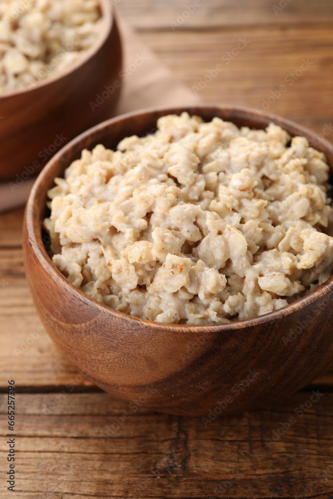 Tasty boiled oatmeal in bowl on wooden table, closeup Tasty boiled oatmeal in bowl on wooden table, closeup