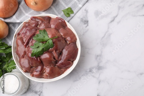 Bowl of raw chicken liver with parsley on white marble table, flat lay. Space for text